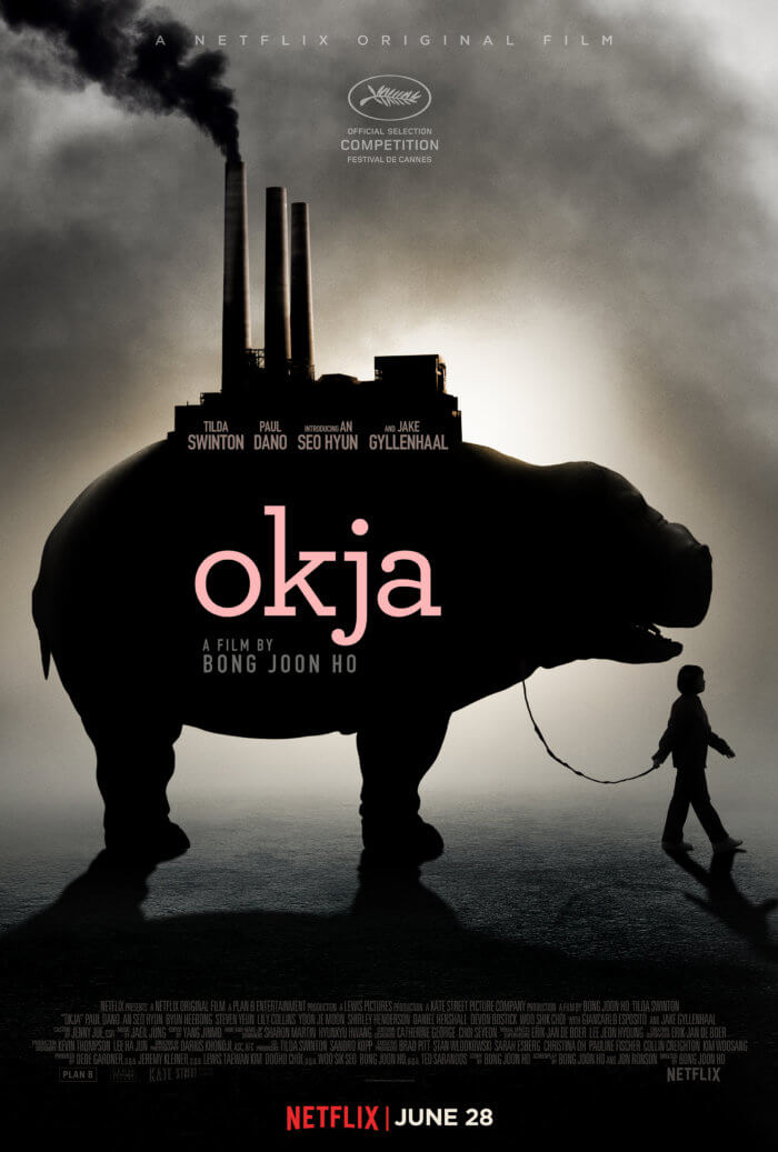 Official movie poster for Okja. Image shows Mija walking in front of Okja with a factory sitting on top of Okja's back and blowing smoke.